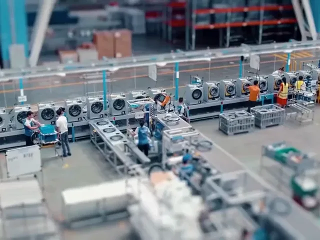 Appliance assembly line with operators fitting panels along a conveyor.